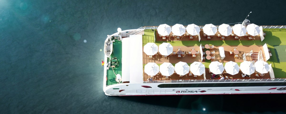 Top view of the sun deck of the river cruise ship A-ROSA with white sun umbrellas and tables on the water.