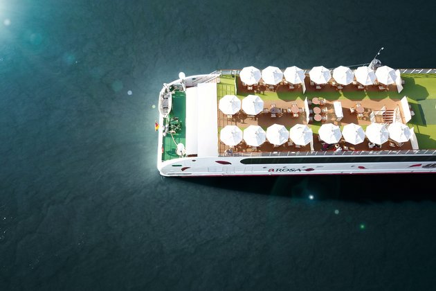 Top view of the sun deck of the river cruise ship A-ROSA with white sun umbrellas and tables on the water.